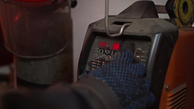 Welder wearing protective glove adjusting settings on digital control panel of welding machine in extreme close up. Video is ideal for industrial manufacturing promotions