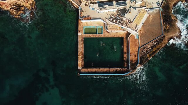 Swimmers Enjoy Coastal Tidal Pool. Drone Captures Lively Seaside Swim Area With Sunbathers