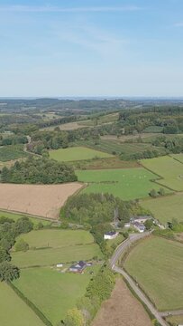 The rural landscape of Morvan, France. The clip features a sweeping view over green fields, scattered houses, forested hills, and a tranquil lake with a shoreline village, aerial vertical 9:16 view.