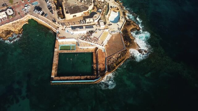 Swimmers Enjoy Coastal Tidal Pool. Drone Captures Lively Seaside Swim Area With Sunbathers