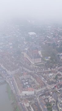 The city center of Gien, France, captured on a foggy day, aerial vertical 9:16 view.