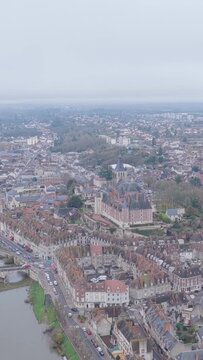 The historic city center of Gien, France, showcasing the distinctive rooftops, winding streets, and the prominent castle and church, aerial vertical 9:16 view.