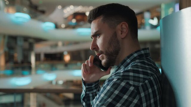 Side view Caucasian business man serious talking mobile phone call discussing news talk smartphone indoors male guy communicate cellphone businessman discuss calling with smartphone in shopping mall