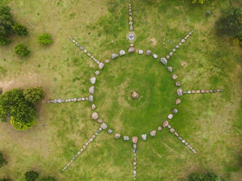 Aerial view of the stone sun dial at the Lithuanian Museum of Ethnocosmology, featuring a circular arrangement of boulders on a green lawn in Kulionys, Utenos apskritis, Lithuania.