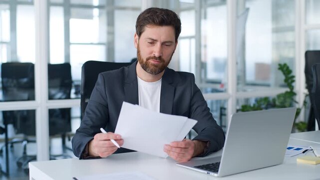 Concentrated Caucasian middle-aged business man signing documents joyful smiling looking at camera happy mature businessman male executive writing noting in papers documentation smile at office table
