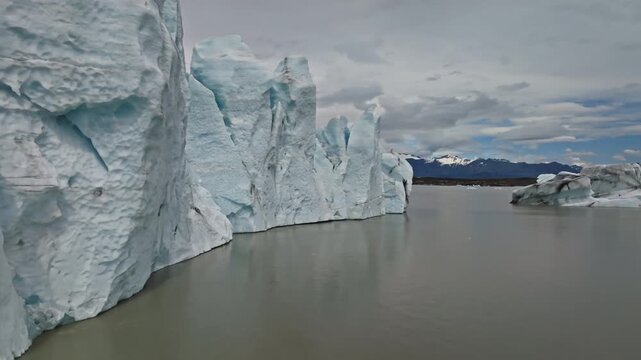 Cinematic aerial flight above the spectacular glacier front of Fjalls&aacute;rl&oacute;n Glacier Lagoon in Iceland, revealing deep crevasses, blue glacial ice and the dramatic landscape of Vatnaj&ouml;kull.