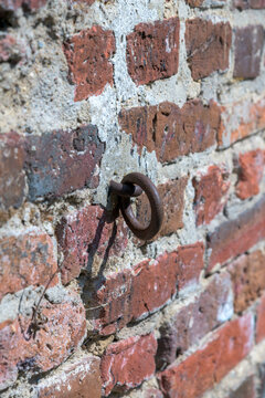 Close up of rusty iron tie ring mounted on old weathered red brick wall
