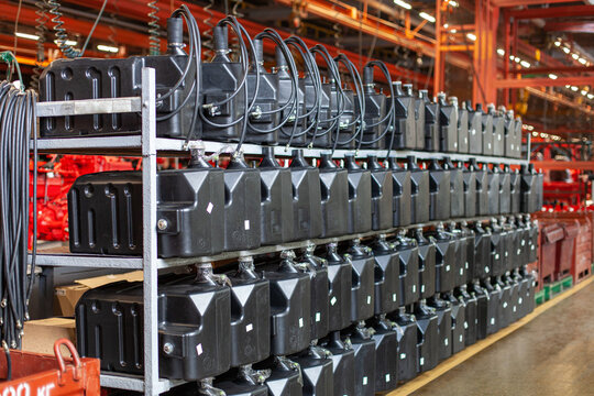 Rows of black plastic fuel tanks stored on metal shelves in heavy manufacturing plant.Industrial manufacturing, supply chain, and automotive production.