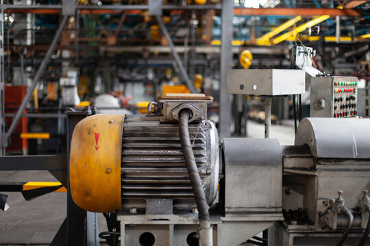 Industrial electric motor and mechanical equipment inside tractor manufacturing factory workshop. Automation, heavy machinery, mechanical power, technical production, industrial maintenance.