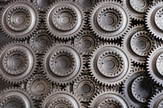 Close-up view of interlocking metal gears and mechanical parts in factory setting. Industry, precision engineering, teamwork, complexity of manufacturing, mechanical design, technology, innovation.