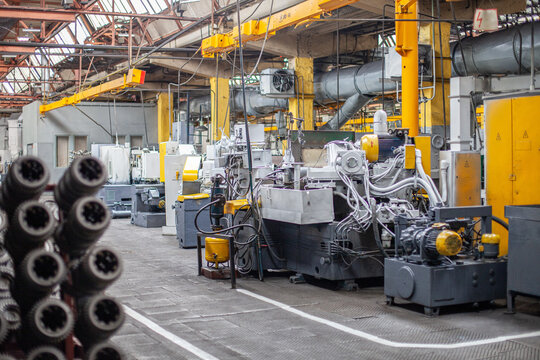Interior view of heavy machinery manufacturing plant with industrial equipment and yellow structural elements. Complex infrastructure of tractor factory, automation, modern metalworking facilities.