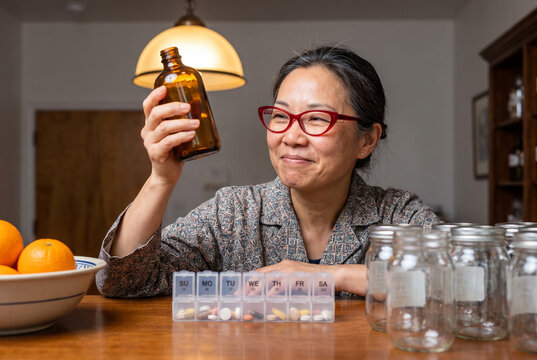 Supplement routine at home with woman sorting pills and jars on a dining table