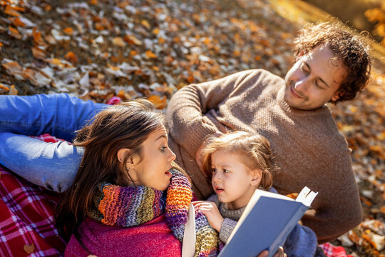 Close family reading together on autumn picnic blanket