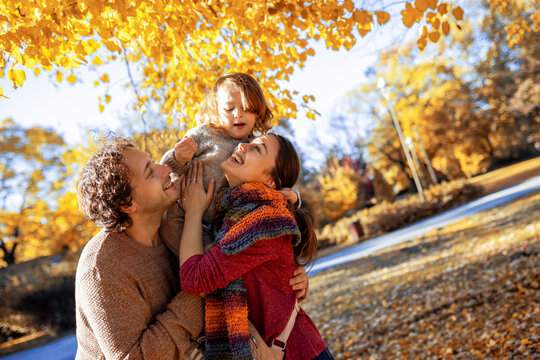 Playful father lifting son on shoulders in fall park