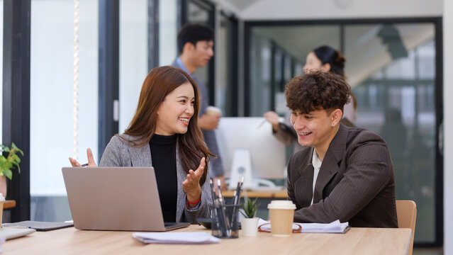 Young business colleagues discussing a project together beside a laptop in the office.