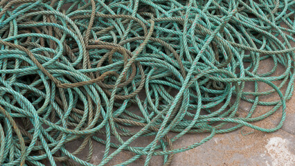 Coiled turquoise fishing rope piled on a concrete quay, abstract maritime texture © Svetlana