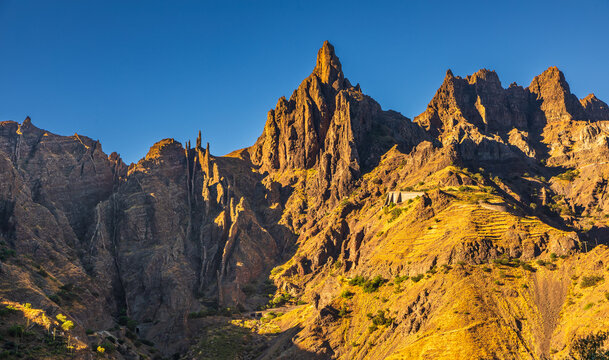 View of the rugged mountain peaks of Santo Antao at golden hour, featuring dramatic rocky cliffs and terraced slopes in Alto Mira, Porto Novo, Cabo Verde.