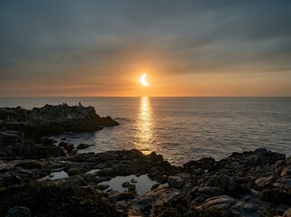 Fototapeta premium Serene Twilight Eclipse Over Rocky Coastal Shoreline with Silhouetted Figures and Glowing Golden Horizon