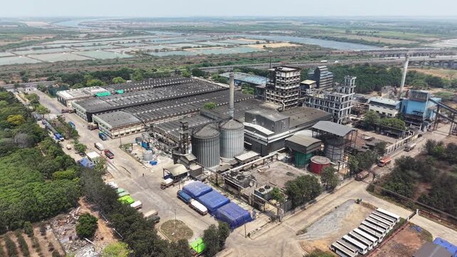 Aerial view of the distillery factory complex with large silos, industrial buildings, and trucks parked in the yard in Nellore, Andhra Pradesh, India.
