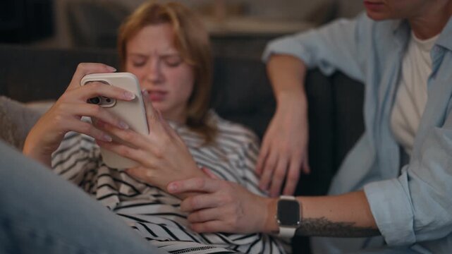 Concerned mother trying to communicate with her teenage daughter who is distracted by her smartphone, showing parenting challenges, generation gap and difficulties in family communication.