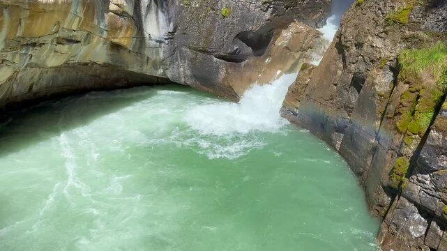 Johnston Creek river in Johnston Canyon in the Banff National Park. British Columbia, Canada. River water flows rapidly through a rocky canyon, showcasing vibrant green colors and textured stone forma