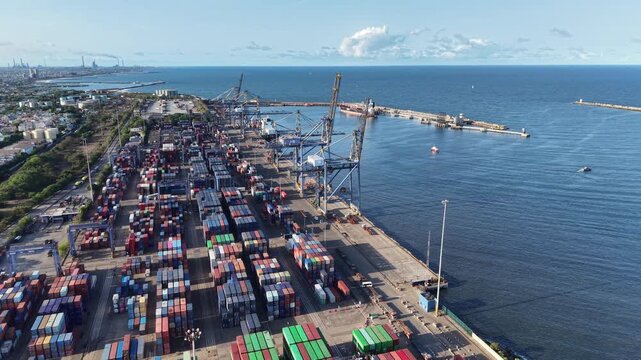 Aerial view of container terminal with rows of colorful shipping containers, large cranes, and ships docked at the harbor in Chennai, Tamil Nadu, India.