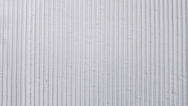 White concrete wall showing a modern textured surface with strong vertical lines and a relief pattern, creating an abstract background for design projects and architectural concepts