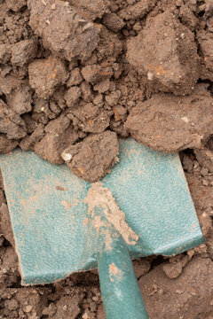 Digging clay soil, poor quality heavy top soil, being dug in a garden background backdrop. Home gardening chore concept
