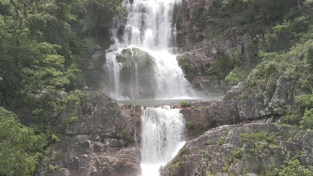 Aerial view of the cascading waterfall at Chapada dos Veadeiros surrounded by lush green forest and rocky cliffs in Alto Paraiso de Goias, Goias, Brazil.