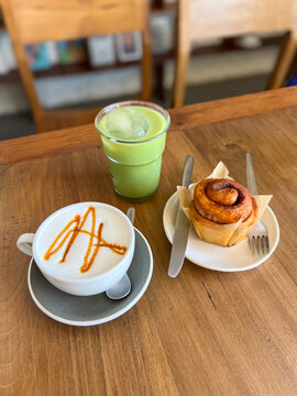Coffee and Matcha Latte with Cinnamon Roll on Wooden Table