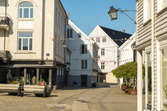 View of the historic white wooden buildings and cobblestone street decorated with colorful flags in the town center of Mandal, Agder, Norway.