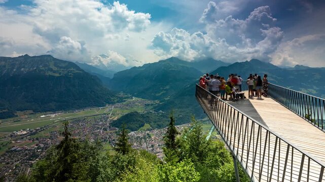 Timelapse of Harder Kulm viewing platform overlooking Interlaken valley with rushing clouds and towering Swiss Alps peaks