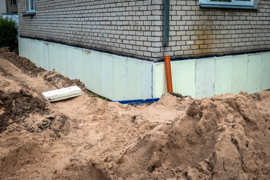 Rigid Foam Insulation Installed Around an Excavated Brick House Foundation