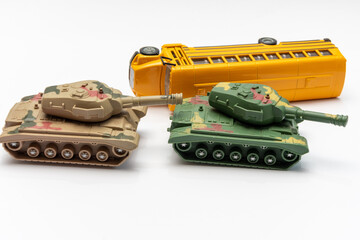 Two toy tanks facing each other beside overturned yellow school bus © Anelo