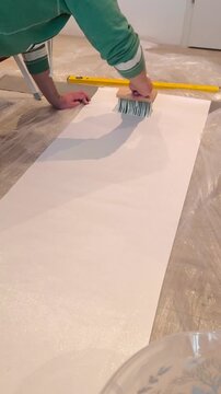 Applying wallpaper paste to the wallpaper strip on the floor