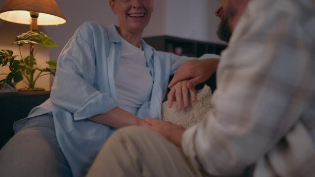 Happy couple sitting together on a sofa at home and laughing, enjoying a joyful moment that represents love, emotional connection, relationship happiness and quality time together.