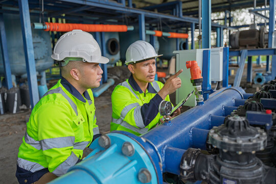 Technicians and engineers inspect a pressure gauge and industrial water pipeline system. Concept of engineering, water management, technical inspection, utilities, and industrial operations.