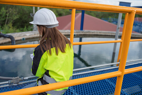 Female engineer recording inspection data at a water treatment plant. Concept of water quality, utility operations, environmental engineering, infrastructure and safety.