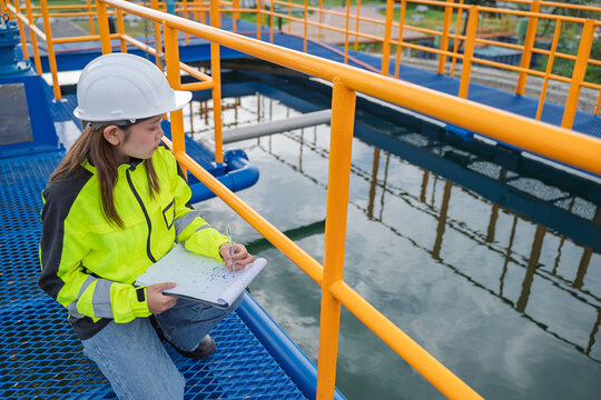 Female engineer recording inspection data at a water treatment plant. Concept of water quality, utility operations, environmental engineering, infrastructure and safety.