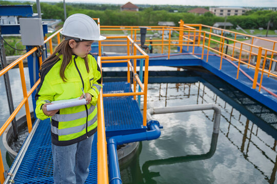 Female engineer recording inspection data at a water treatment plant. Concept of water quality, utility operations, environmental engineering, infrastructure and safety.