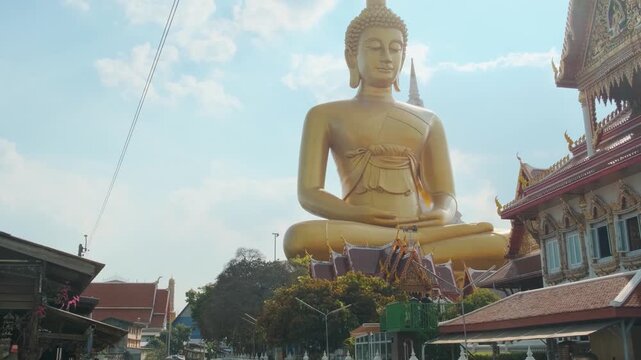 Golden Big Seated Buddha statue along Bangkok canal at Wat Paknam Phasi Charoen temple, Thailand. Urban waterway scene combining transport, culture and religious architecture.