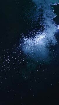 Vertical video: Green glove dropping tablet into rim tank on table, spotlight creating foam plume