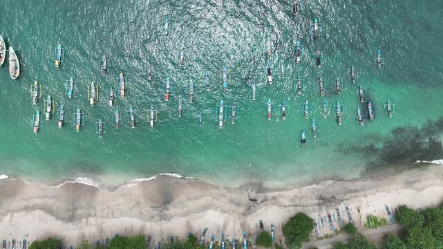 Aerial view of traditional fishing boats anchored in the turquoise waters off the sandy coast of Lumajang, East Java, Indonesia.