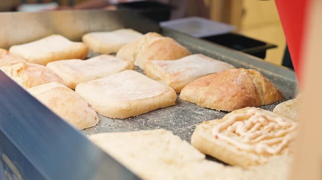 Baked goods are arranged on a countertop in a bakery, showcasing different types of bread and pastries.