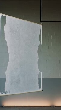 Vertical video: Rotating thin panel on cords tilting in studio, showing depth, rod and wall light