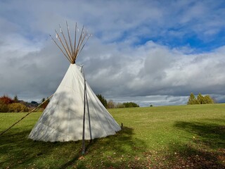 Tipi Tent on Grassy Field with Cloudy Sky © flucas