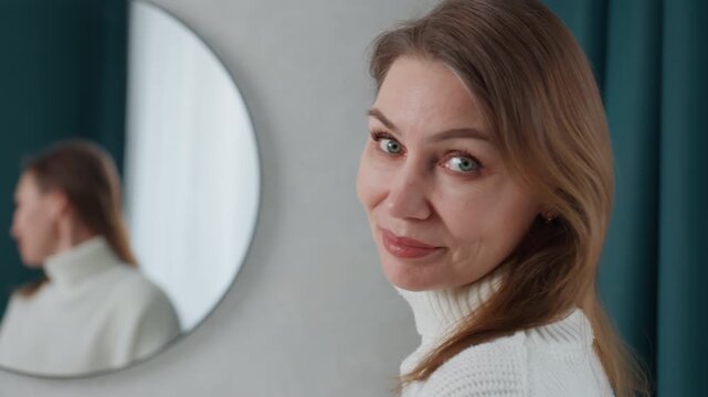 Instructor Looks into Mirror Sensing Tranquility and Encouragement. Caucasian instructor smiling at mirror portraying peaceful contentment and thoughtful reflection during relaxation