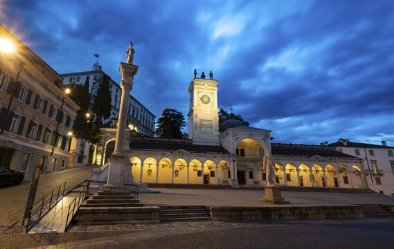 Illuminated main square Piazza della Libert&agrave; with Loggia e Tempietto di San Giovanni and clock tower, Castello di Udine behind, blue hour, dramatic sky, old town, Udine, Friuli-Venezia Giulia, Italy