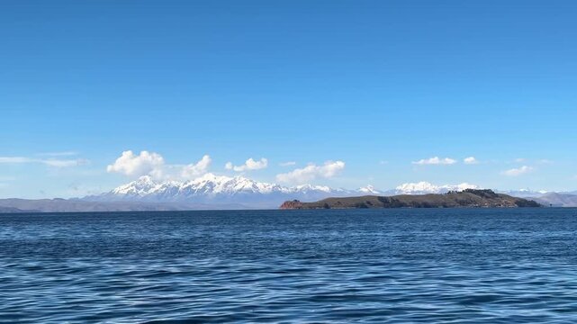 Vista panor&acirc;mica do Lago Titicaca com a Cordilheira Real e picos nevados ao fundo, Bol&iacute;via. Paisagem calma de &aacute;gua e montanhas dos Andes sob c&eacute;u azul.
