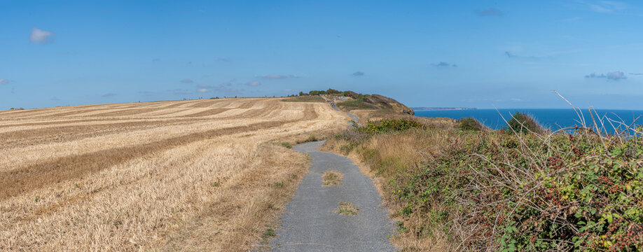 Arromanches-les-Bains, France - 08 10 2026: Coastal path. Panoramic view of the dried cultivated fields on top of the cliffs during the heatwave